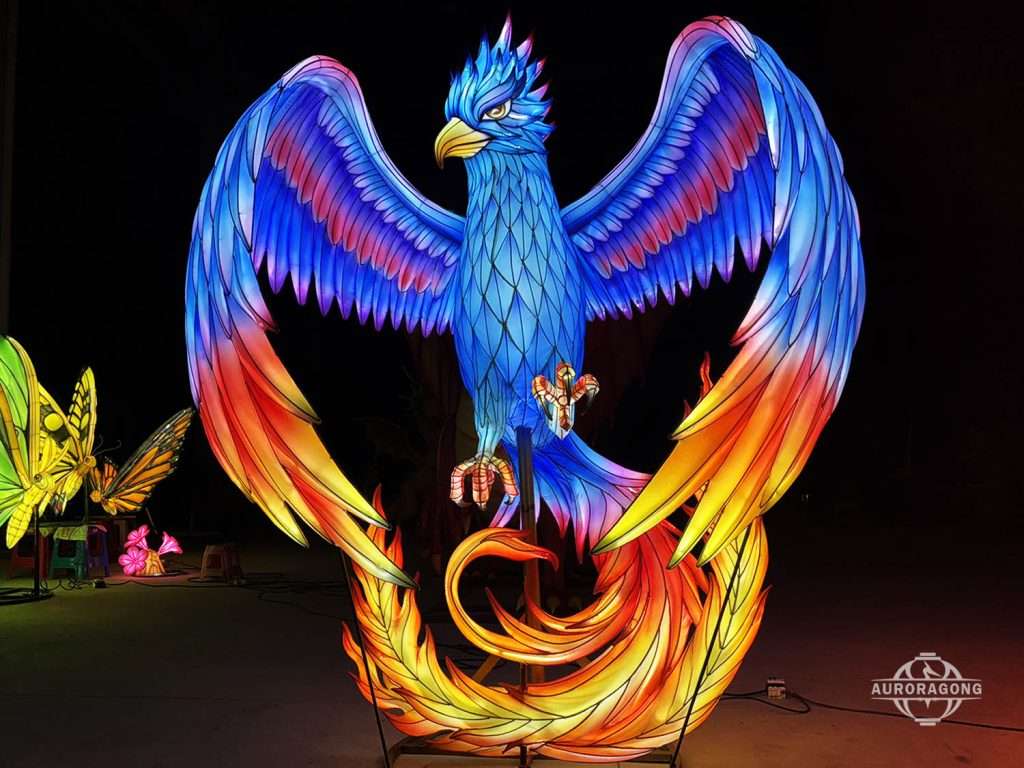 Custom illuminated blue phoenix lantern with detailed feathered wings and flame tail at night festival display