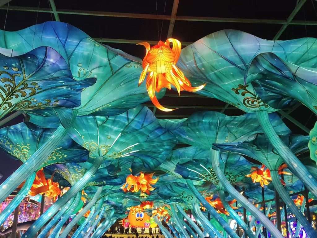 Immersive blue and green ocean themed lantern tunnel archway with golden flower and cartoon sea creatures at Zigong International Dinosaur Lantern Festival