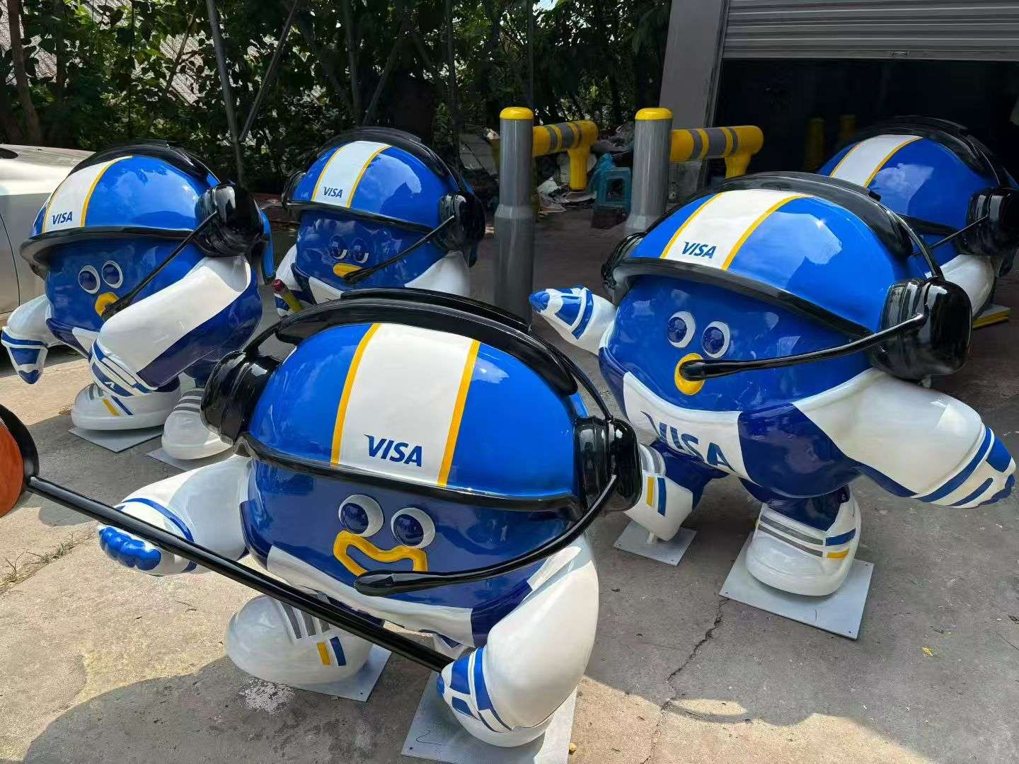 Custom VISA branded IP character figurines with blue helmets as themed sculpture accessories in workshop yard