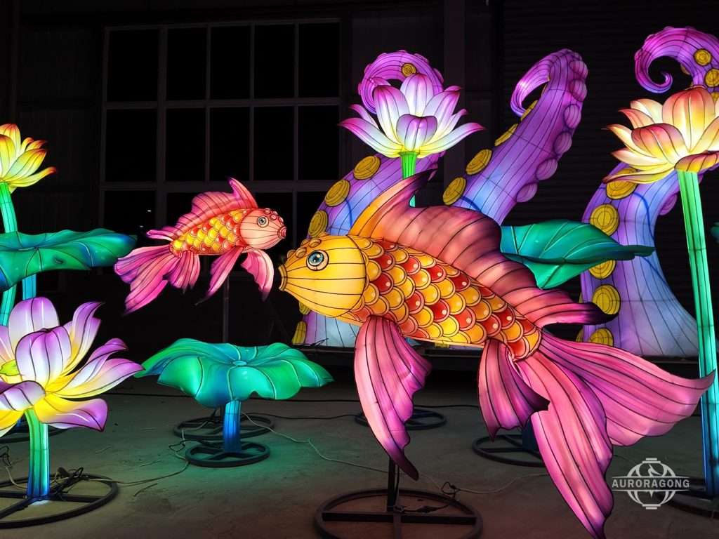 Custom illuminated vibrant koi fish and lotus flower lantern display in pink, orange, purple, and green