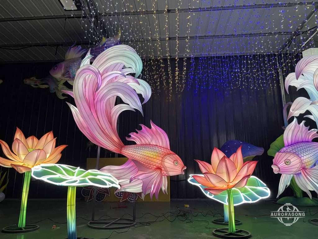 Illuminated pink betta fish lantern with lotus flowers and blue star curtain in factory workshop display