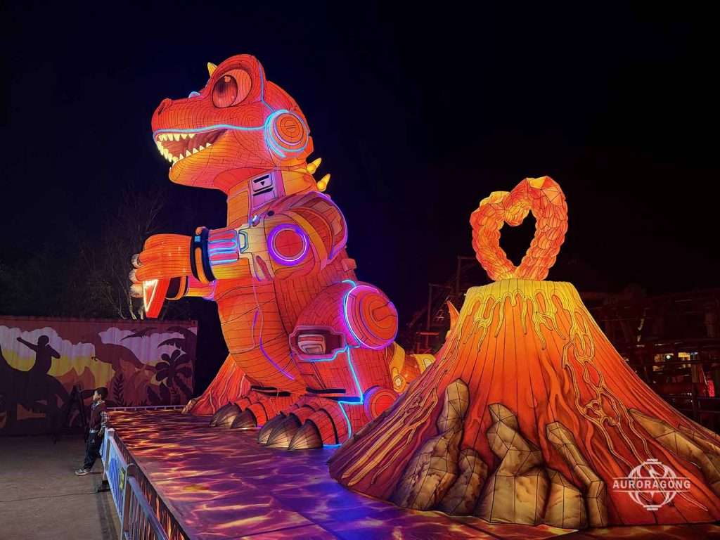 Custom mechanical T-Rex and orange volcano dinosaur lantern display at night theme park festival