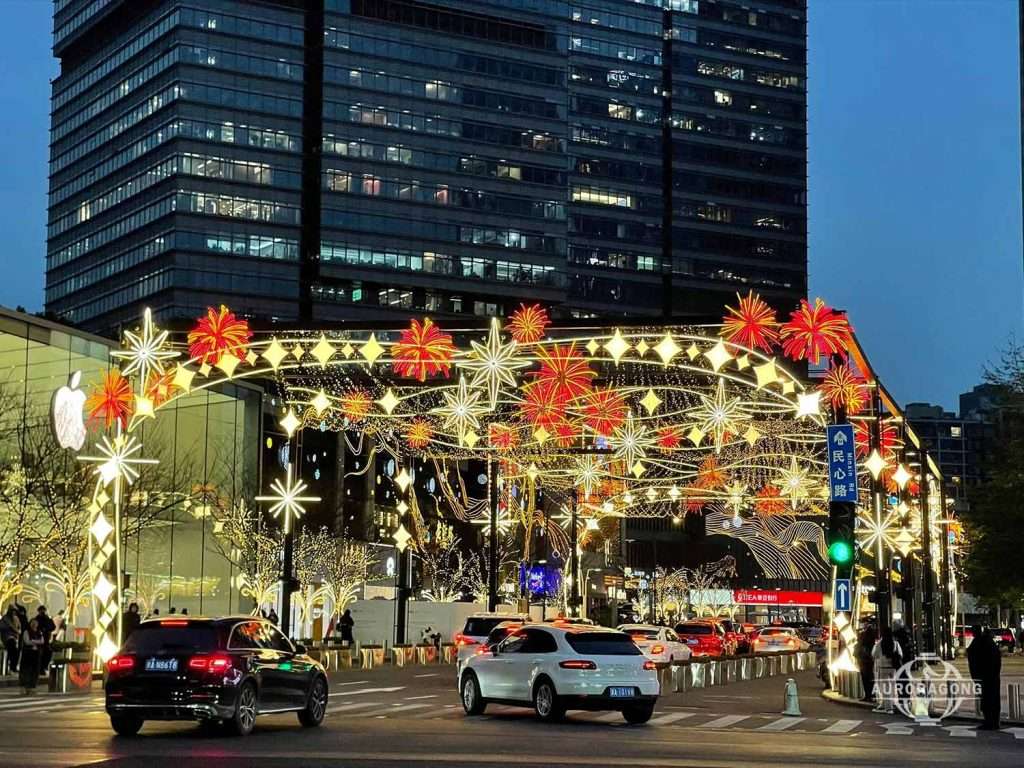 Custom colorful LED passage light arch with red fireworks and star decorations over a city commercial street at dusk