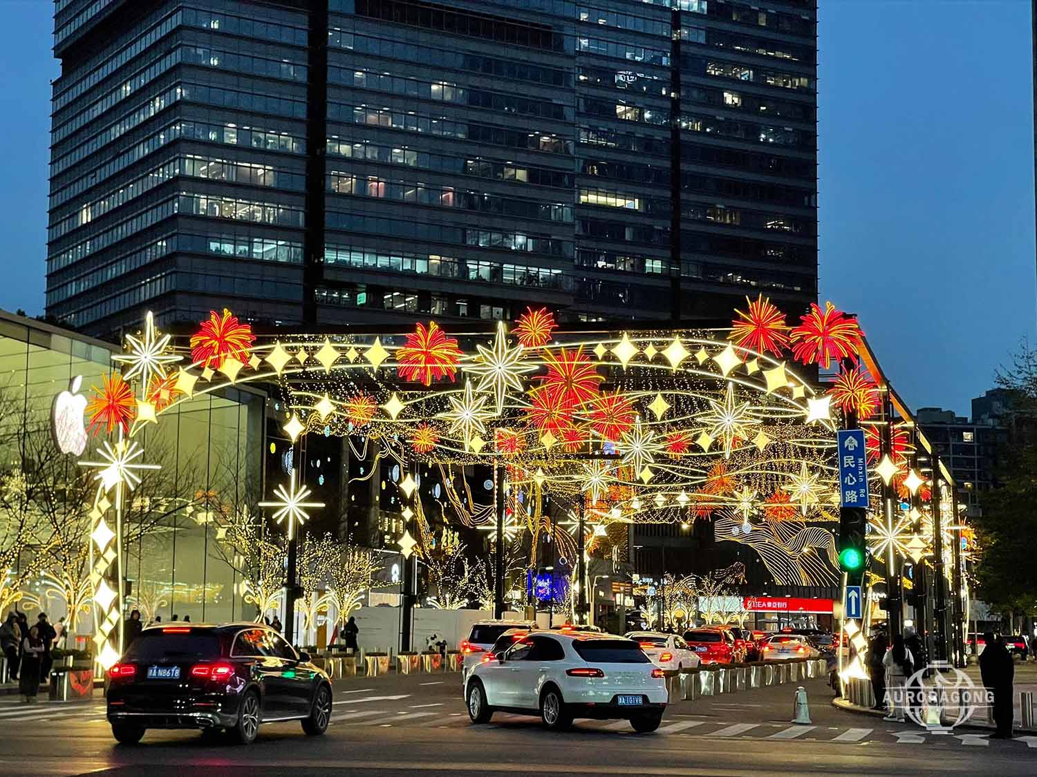 Custom colorful LED passage light arch with red fireworks and star decorations over a city commercial street at dusk