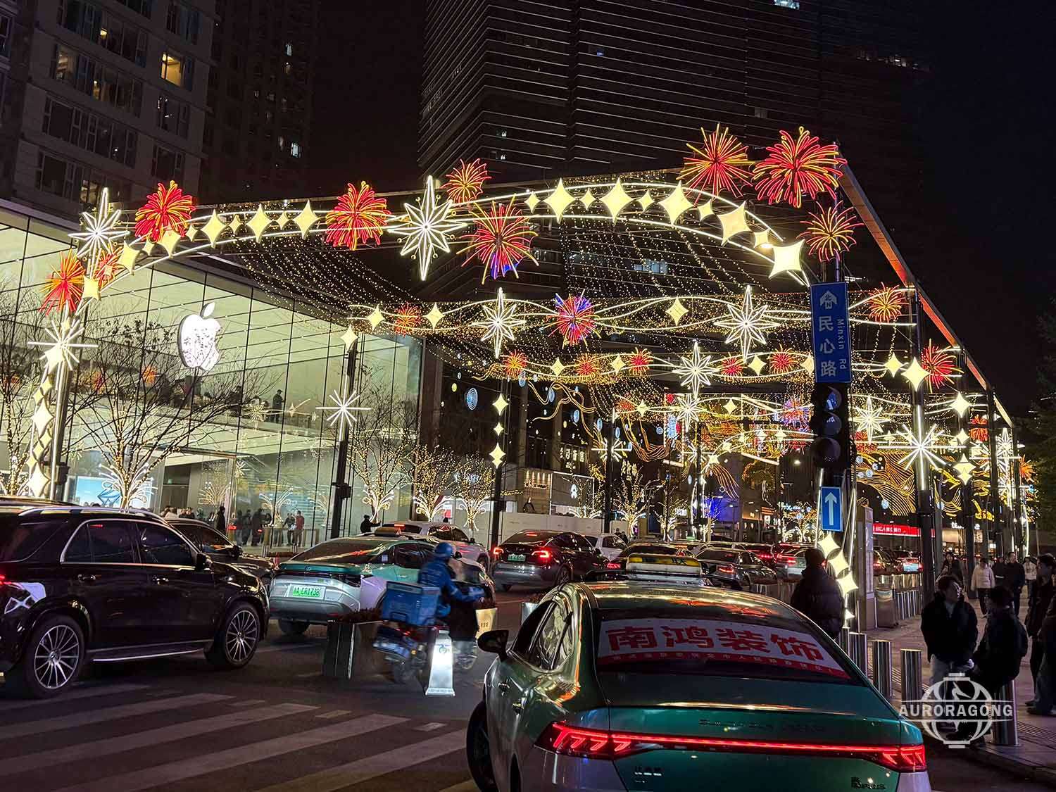 Custom colorful LED passage light arch with star and snowflake decorations across a city street at night with traffic