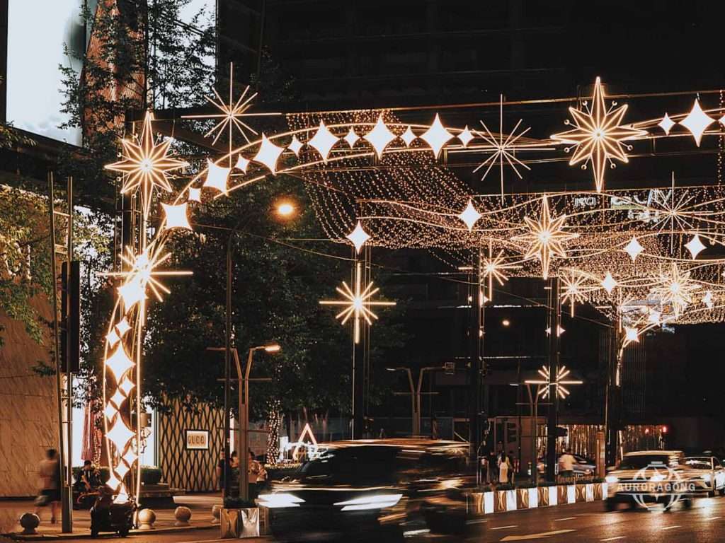 Custom illuminated LED passage light arch with star and snowflake decorations across a city street at night