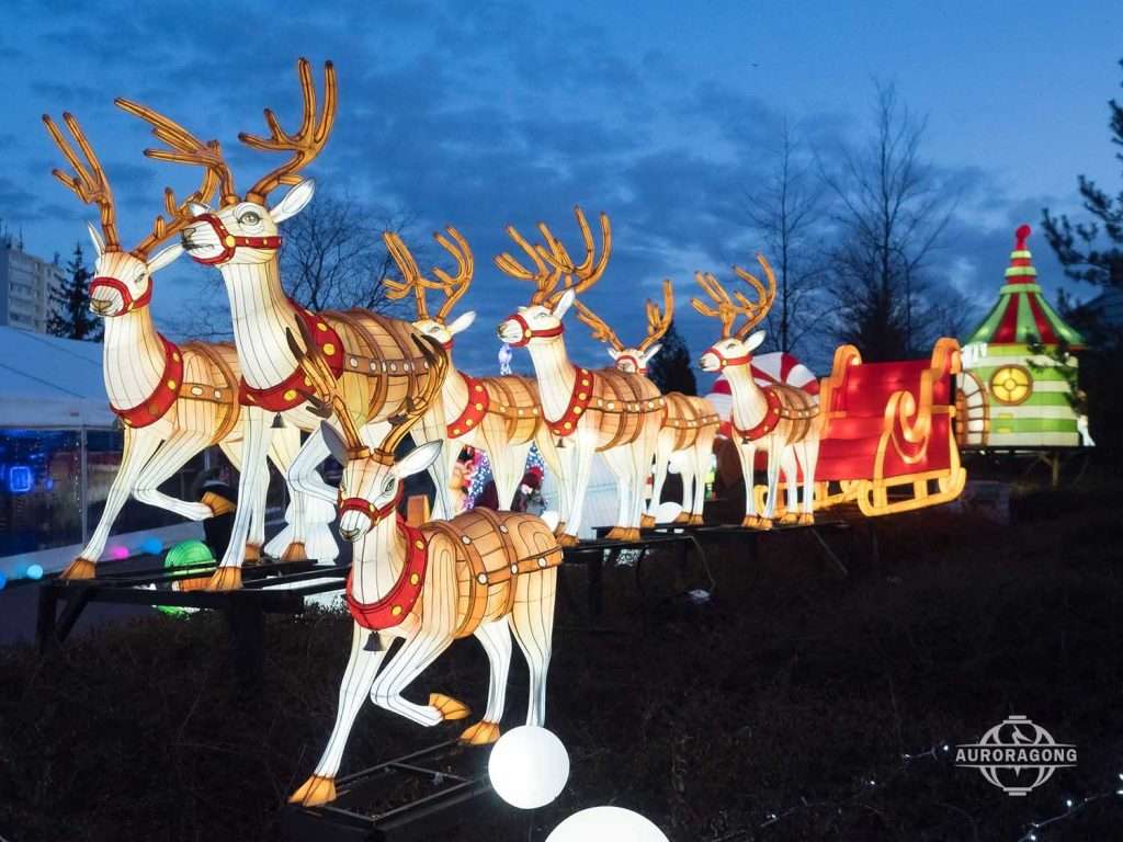Row of illuminated reindeer lanterns pulling Santa's sleigh in an outdoor Christmas display