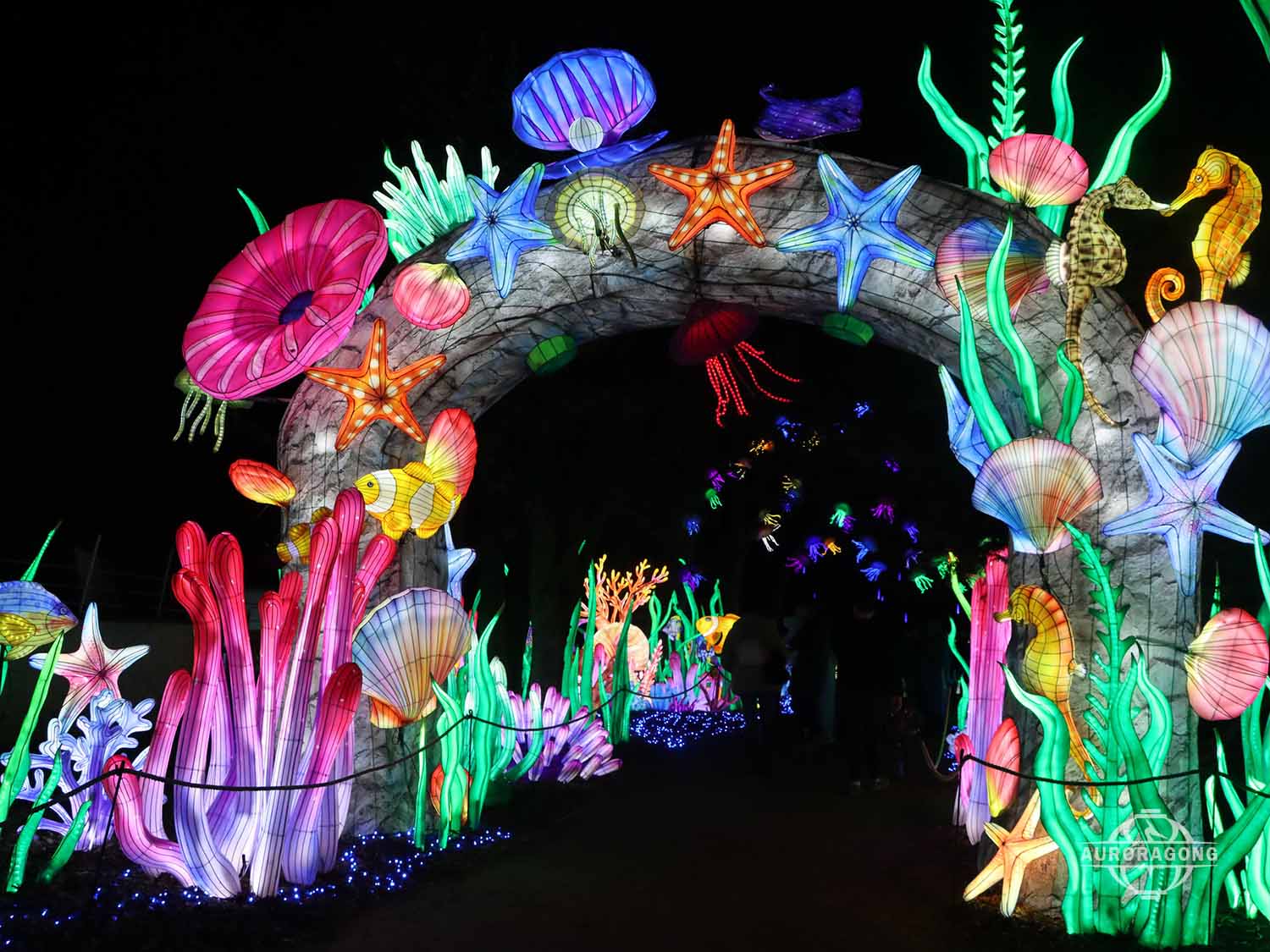 Wide view of illuminated ocean channel archway lantern with starfish, anemones, seahorse, and shell decorations