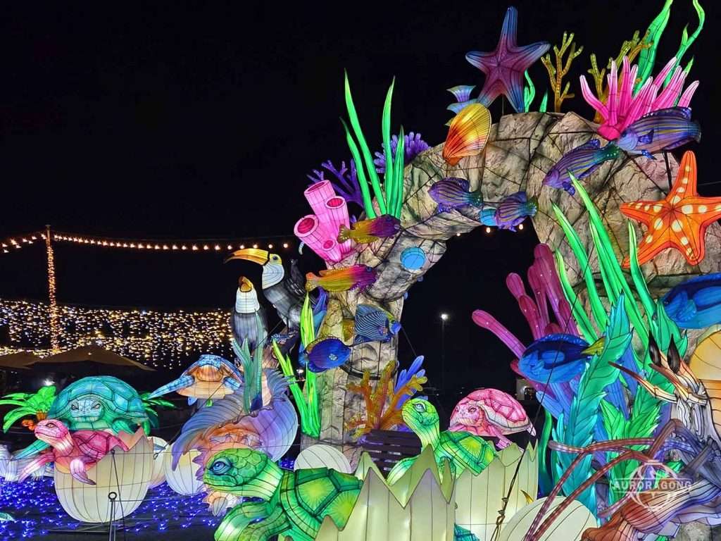 Illuminated ocean channel lantern archway with coral, starfish, seahorse, and octopus at a night festival