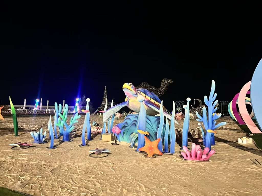 Beachside ocean lantern installation with illuminated fish and coral at night in Kuwait