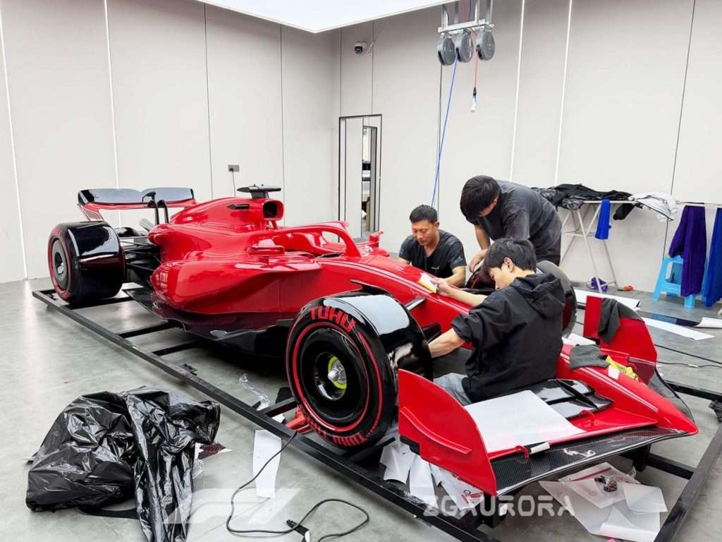 Skilled craftsmen polishing giant F1 race car model