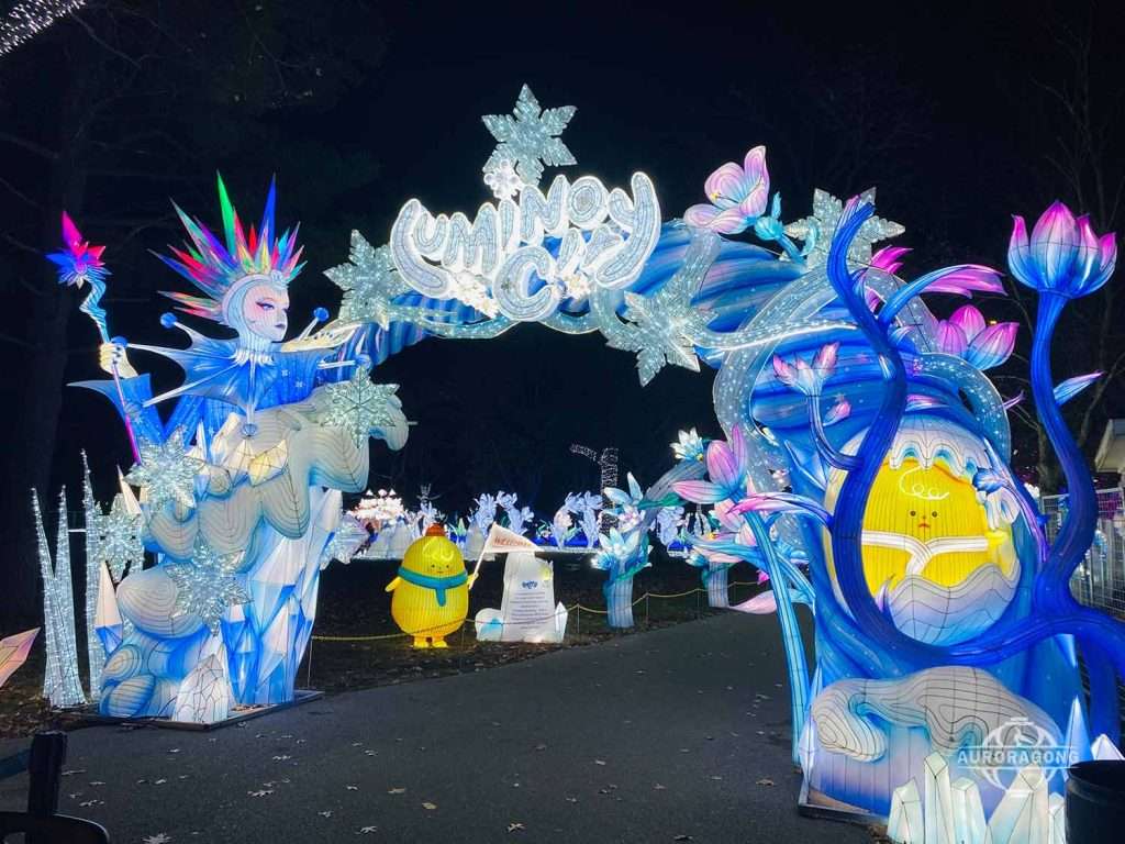 Illuminated ice queen character lanterns with blue botanical arches and star lights at a lumino city night festival