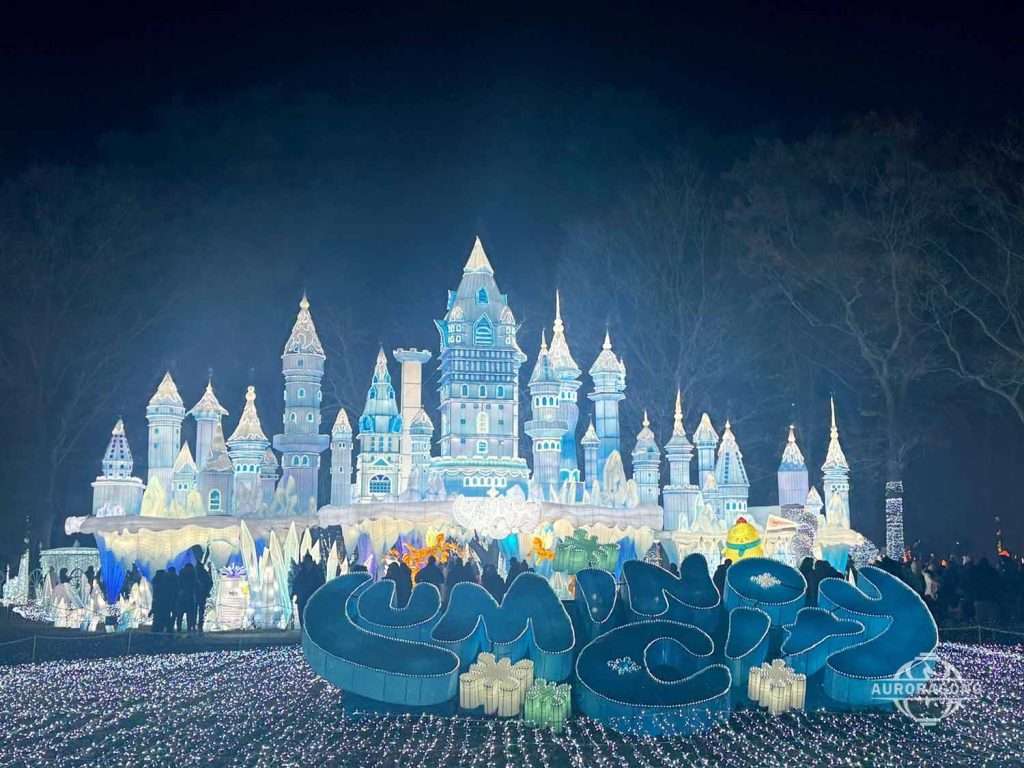 Wide view of illuminated ice castle lantern display with blue wave decorations at a lumino city festival