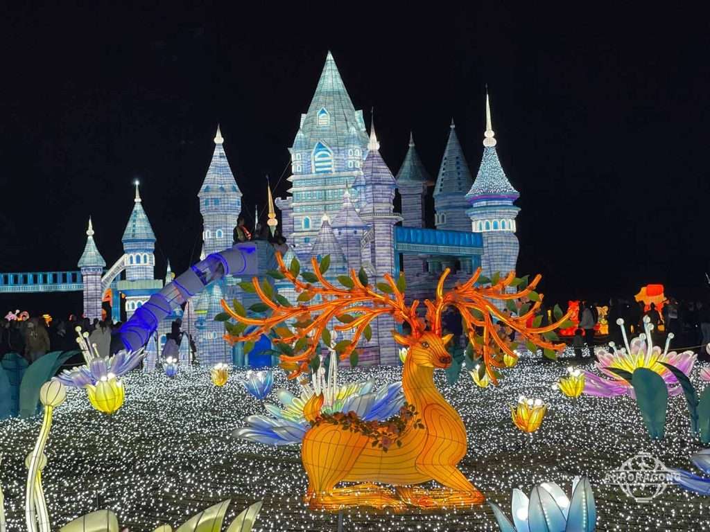 Illuminated ice castle with golden antlered deer and flower lanterns at a lumino city night festival