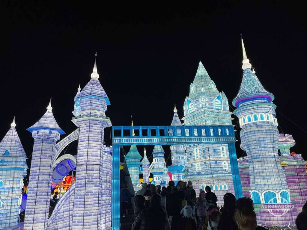 Illuminated ice castle lantern display with blue and purple lights at a lumino city night festival