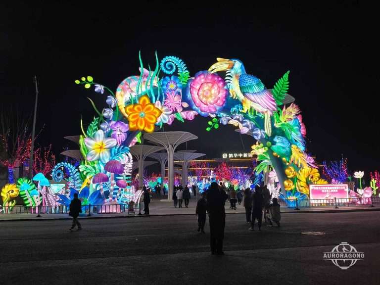 Colorful plant-themed archway lantern with phoenix bird and flowers at a public park at night