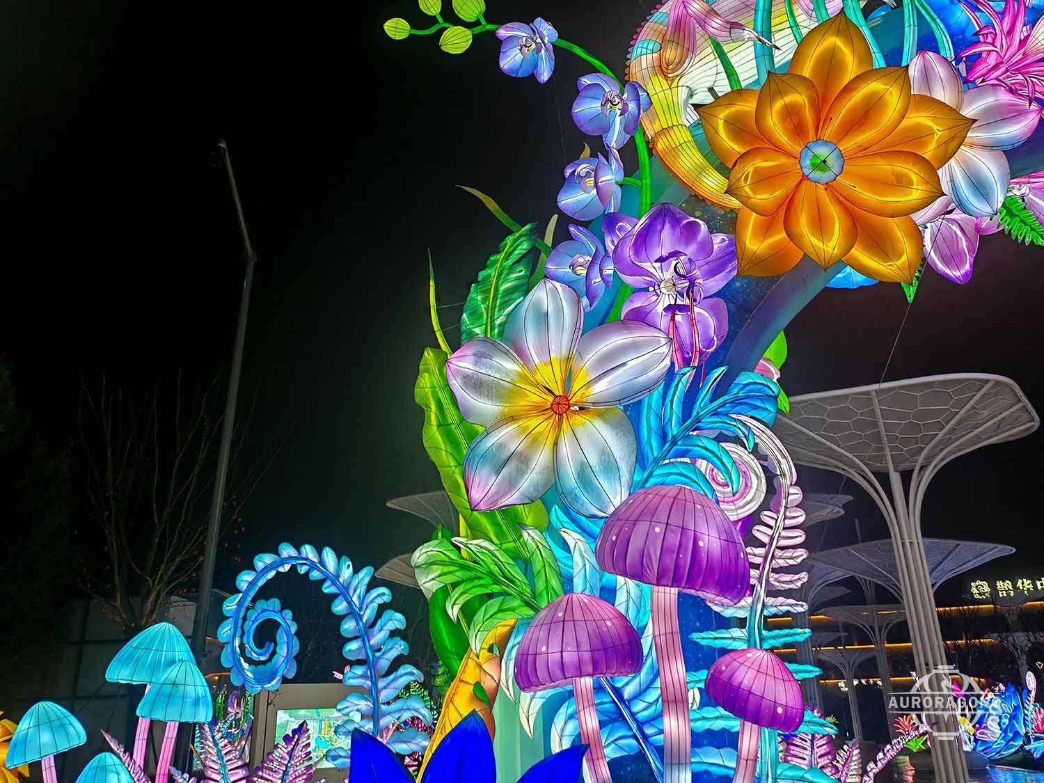 Illuminated tree of life lantern with hibiscus flowers and purple jellyfish at a park pavilion