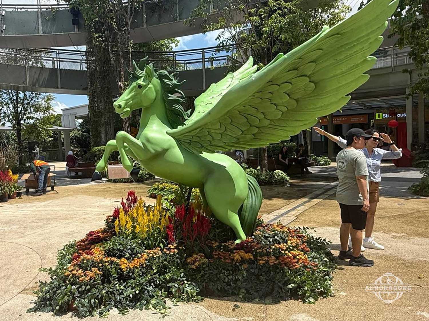 Escultura de Pégaso em fibra de vidro verde em exposição no jardim.