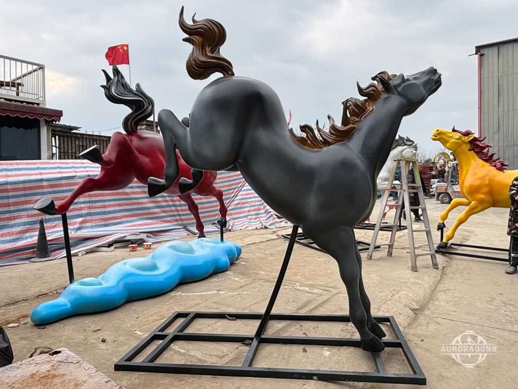 Colorful fiberglass horse sculptures in black, red, yellow, and blue color variants at factory yard