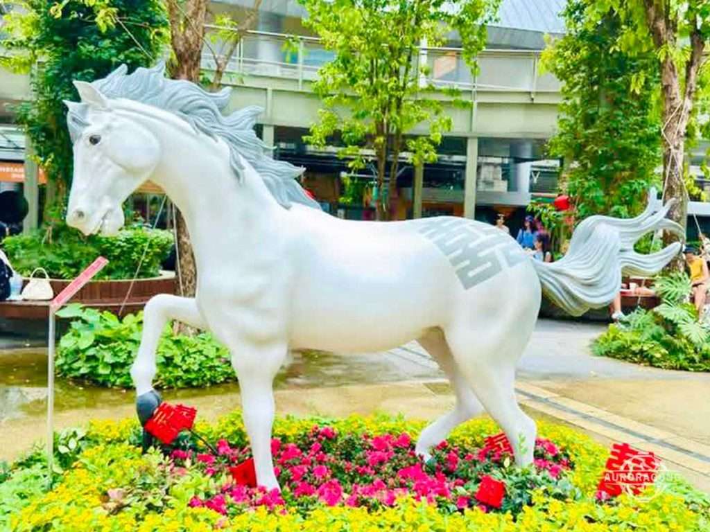 Custom white fiberglass horse statue galloping through a landscaped outdoor garden display