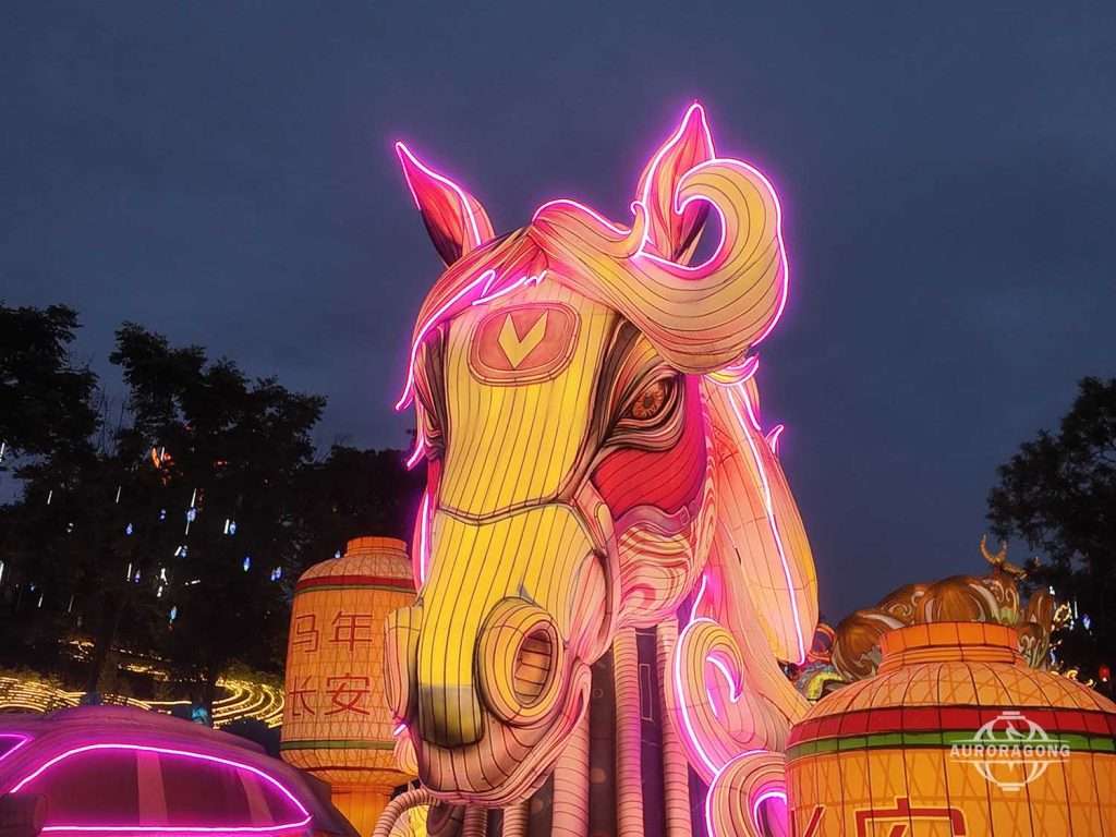 Giant golden-orange illuminated horse head lantern against a twilight sky for a festive event