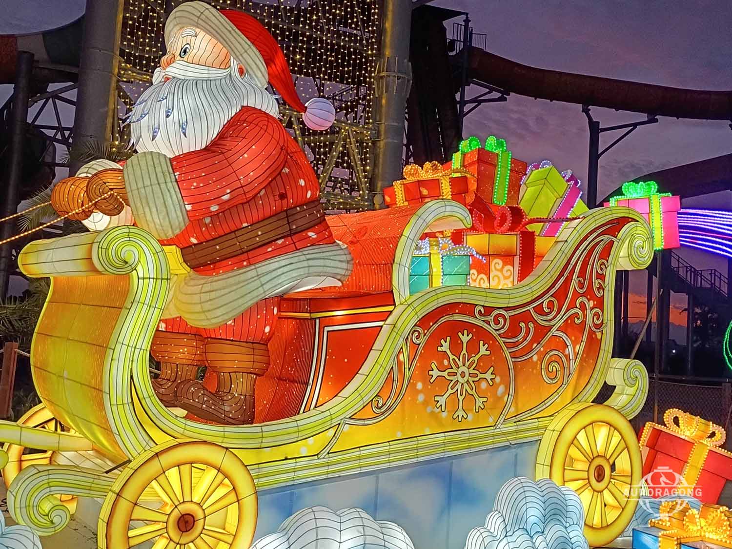 Santa Claus sitting in glowing Christmas sleigh with colorful gifts for holiday festival