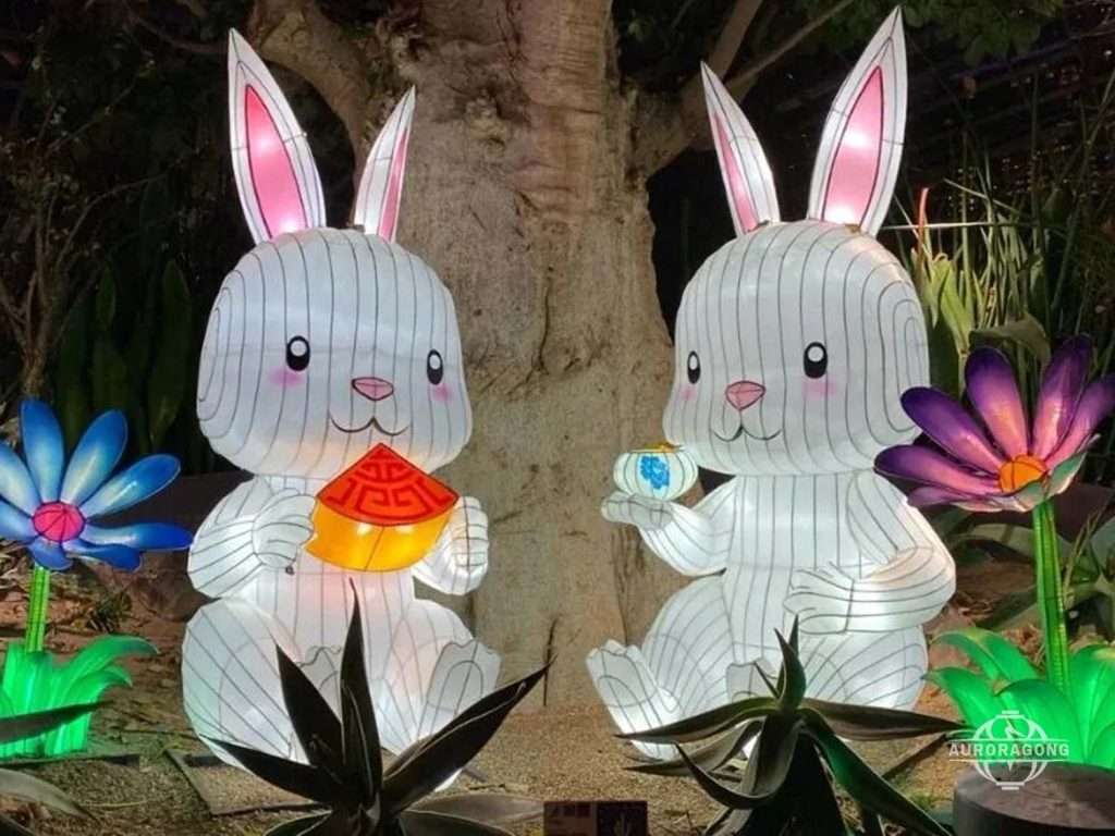 Two illuminated white rabbit lanterns holding decorative items amid colorful lotus lanterns at a Mid-Autumn festival display