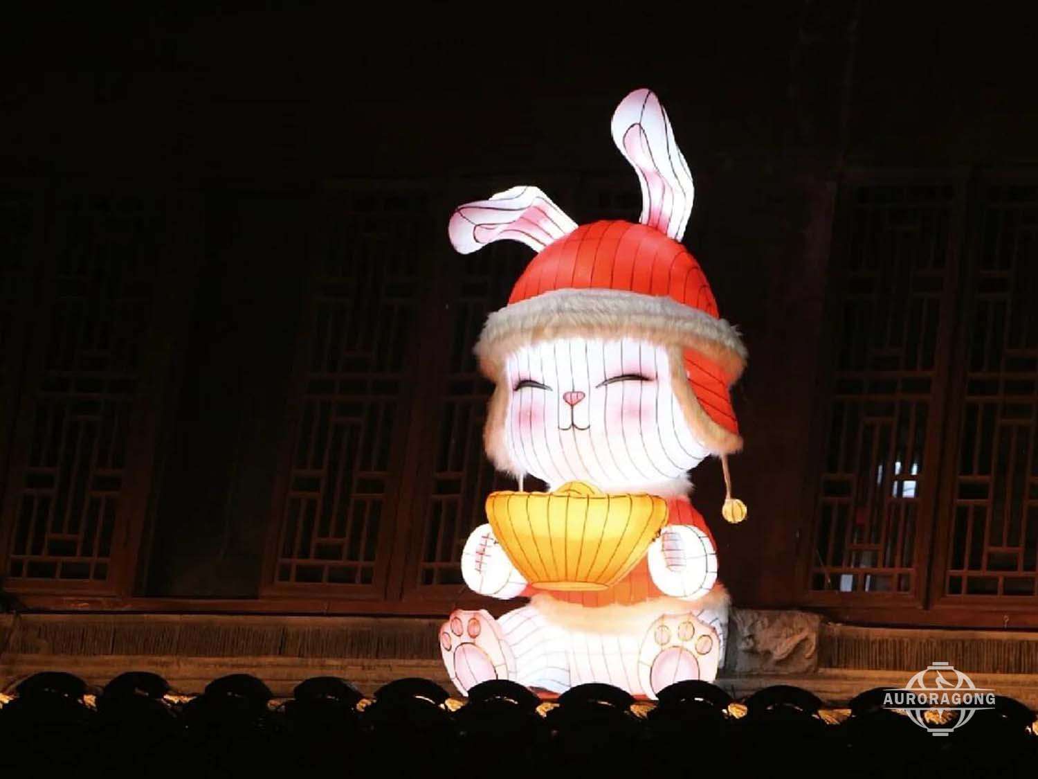 Hotel Mid-Autumn Festival decorative rabbit lantern wearing a red Santa-style hat and holding a yellow fan