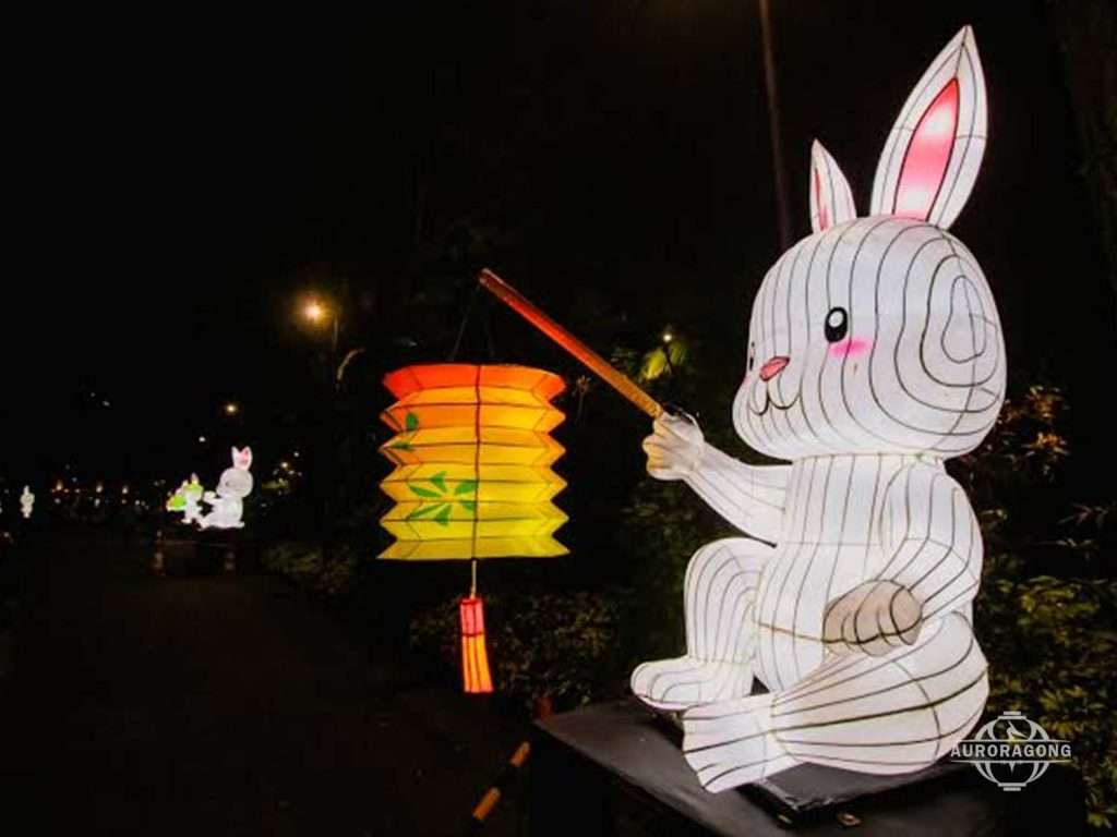 White rabbit-shaped lantern holding a colorful Chinese lantern at a Mid-Autumn festival night display