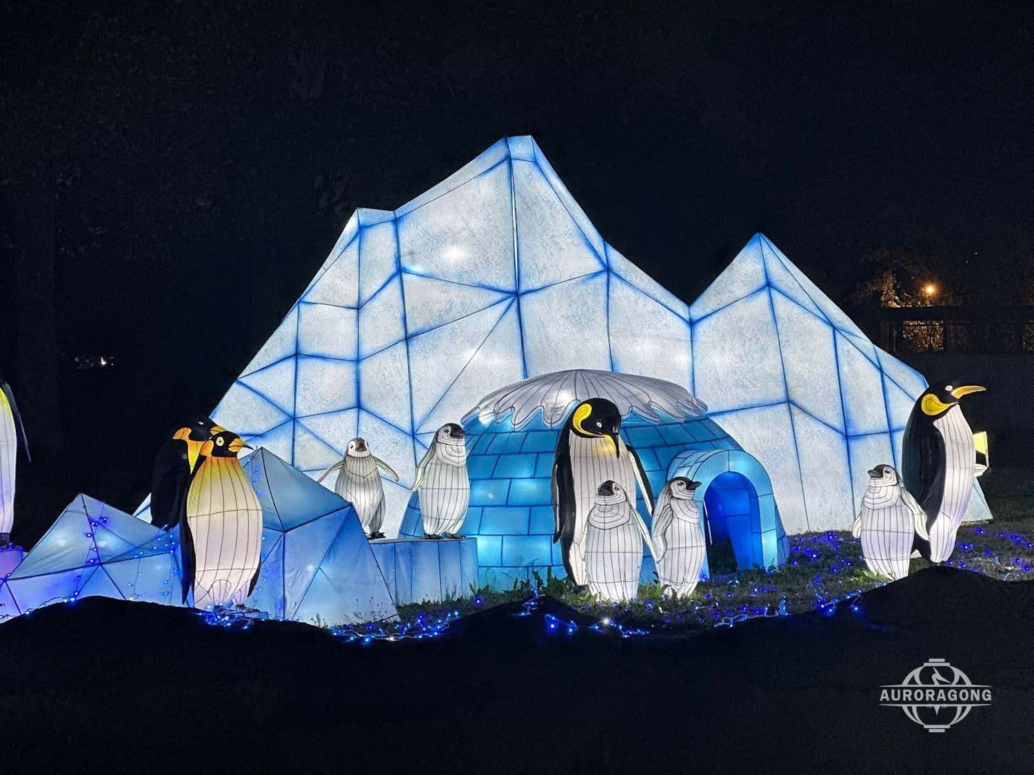 Penguin family lanterns in front of glowing ice cave, Arctic festival display