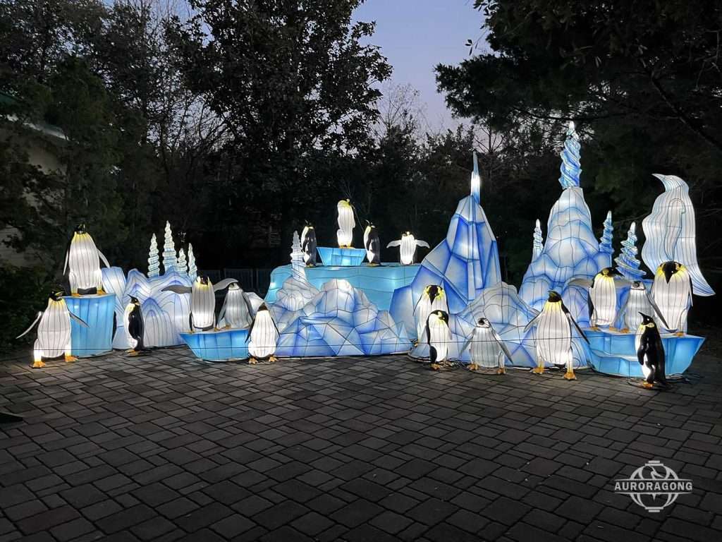 Family of glowing penguin lanterns on an iceberg-themed display with blue LED lighting
