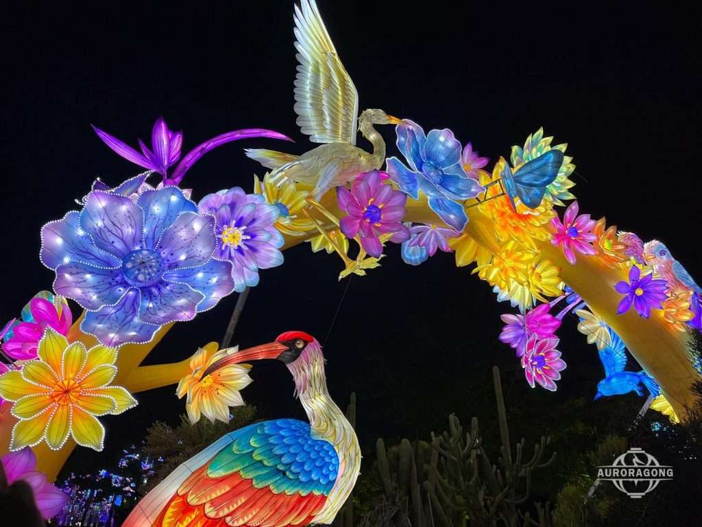 Illuminated archway with white cranes, lotus flowers, and a butterfly