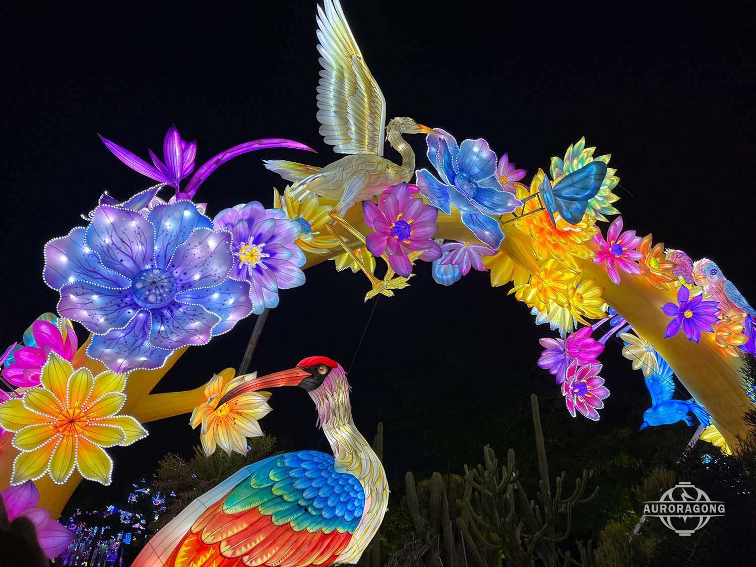 Illuminated archway with white cranes, lotus flowers, and a butterfly