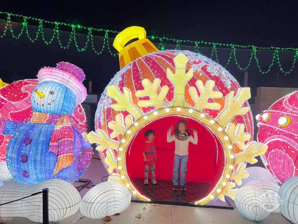 Walk-through illuminated Christmas bauble lantern with snowman lantern at an outdoor winter lantern festival at night